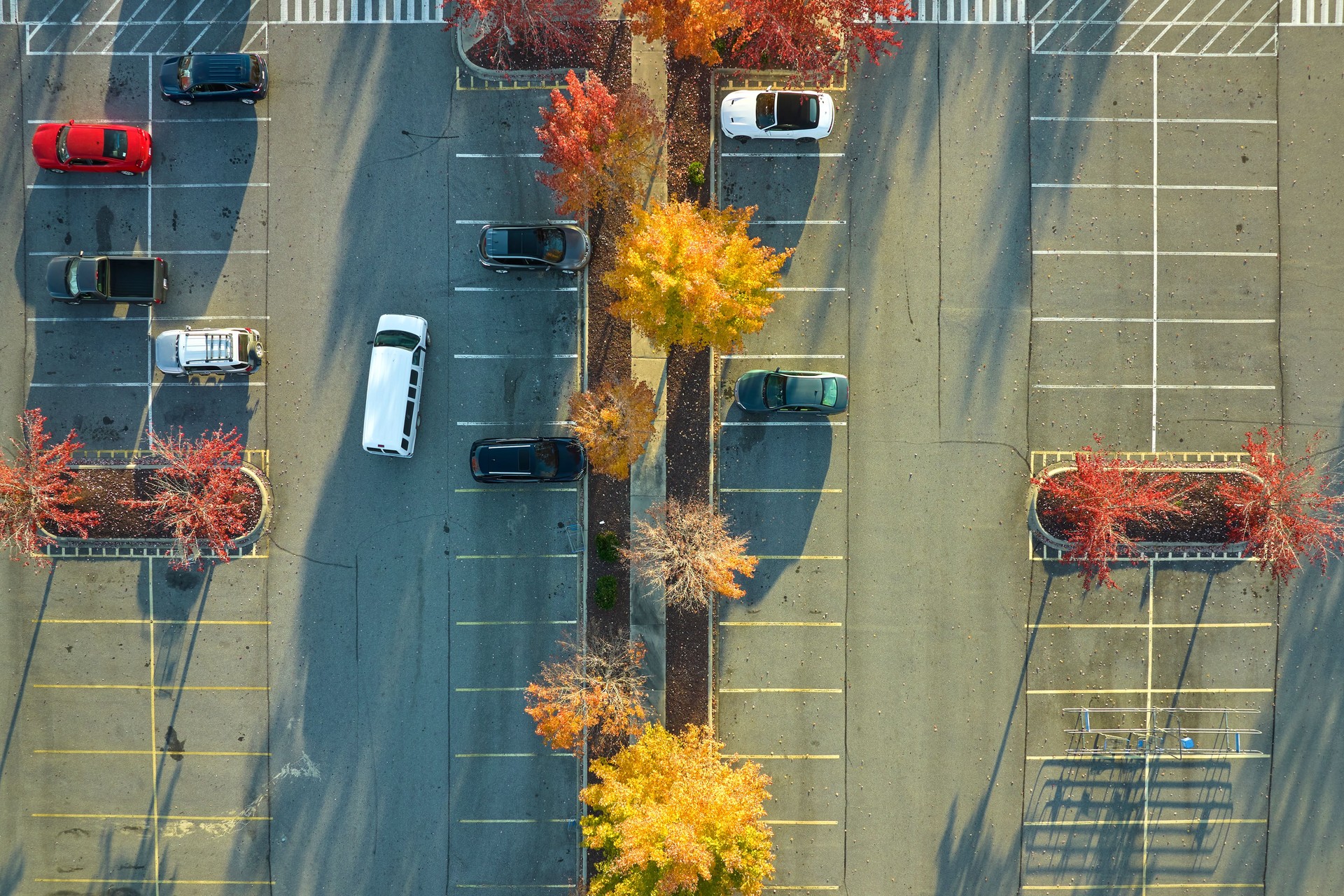 Aerial view of large parking lot with many parked colorful cars. Carpark at supercenter shopping mall with lines and markings for vehicle places and directions